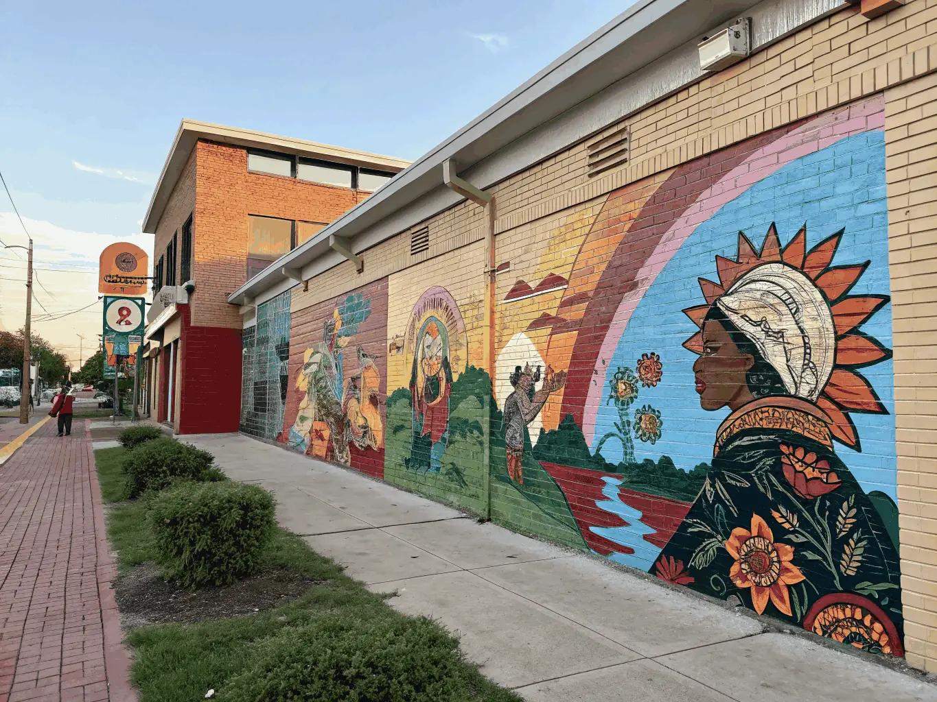A photograph of the 'Colors of Unity' mural in Le Deveix, showcasing the vibrant artwork and the community members who participated in its creation.